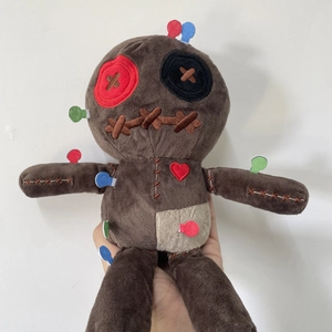 Detailed close-up of brown plush voodoo doll with button eyes and colorful sewing pins