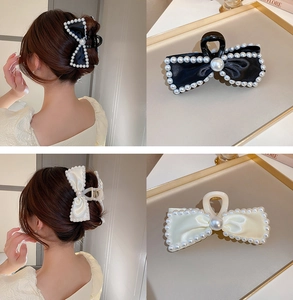 Detail of satin bow hair claws with elegant pearls in black and cream white colors