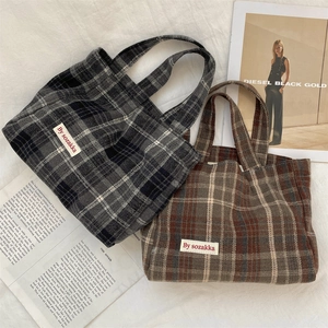 Close-up of vintage plaid tote bags in grey and brown patterns with fabric labels