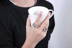 Close-up of a wide two-tone band ring with blue and red heart crystals worn by a model