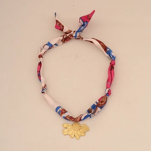 Detailed shot of a floral silk scarf necklace with a golden daisy flower pendant charm