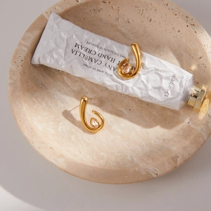 Détail de boucles d'oreilles dorées avec zircone sur présentoir en marbre chic