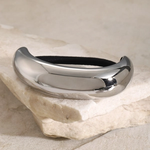 Close-up of polished silver metal ponytail cuff on stone with elastic hair tie