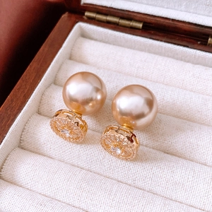 Close-up of vintage 14k gold-plated zircon pearl earrings in a wooden jewelry box.