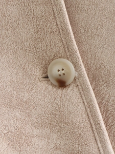 Detail shot of beige textured fabric and elegant marble-patterned four-hole button