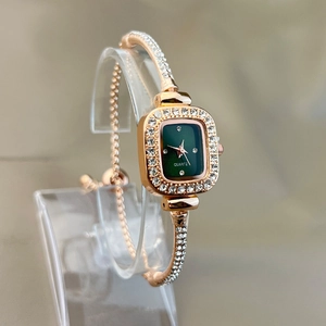Macro detail of rose gold square watch with green dial and rhinestone bracelet