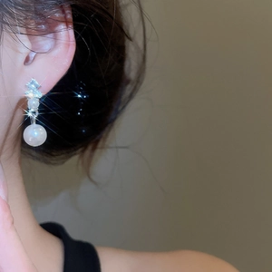 Close-up of elegant silver diamond and pearl earrings on a model for a vintage look
