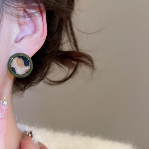 Gros plan d'une boucle d'oreille léopard ronde avec bordure vert armée sur le modèle