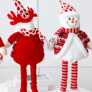 Detail of plush Christmas elk and snowman dolls with knitted textures and festive red hats