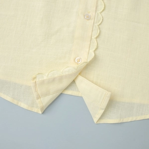 Détail du chemisier crème en coton et lin avec bordures élégantes en dentelle festonnée