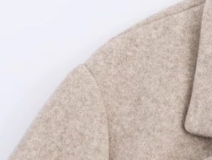 Macro detail of the shoulder stitching and wool blend fabric on a beige blazer jacket