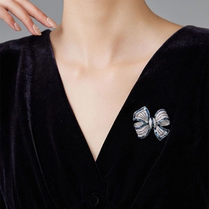 Close-up of bow brooch with blue gemstones and clear crystals on black velvet jacket