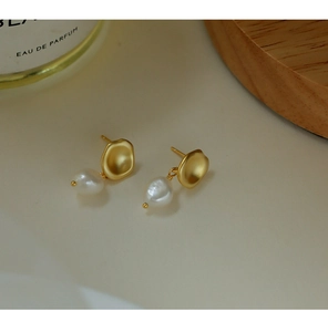 Detailed macro shot of matte gold irregular plates and Baroque pearls on French style earrings