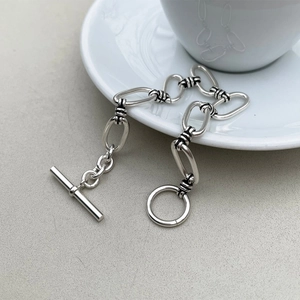 Close-up of a 925 sterling silver chain bracelet with a classic T-bar toggle clasp on ceramic