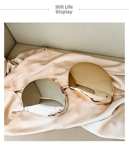 Close-up of pebble-shaped gold and silver mirror-finish metal cosmetic bags on silk