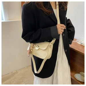 Detail of cream white faux leather bag with golden ring buckle and floral silk scarf charm