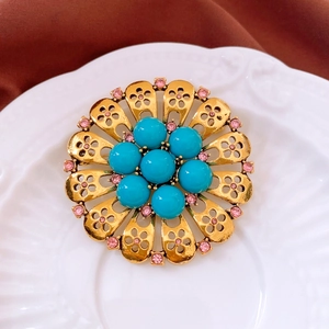 Macro shot of vintage gold flower brooch with turquoise beads and pink rhinestones