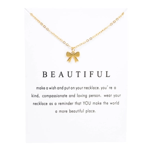 Elegant gold bow pendant necklace on white display card with inspirational message