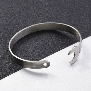 Detail of silver stainless steel wrench bangle with a brushed metal texture and open cuff