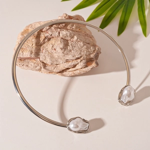 Detail of silver geometric choker collar with white baroque pearls on a natural background