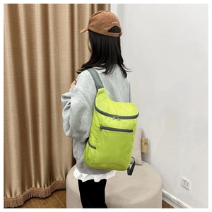 Model wearing fluorescent green folding backpack showing size and fit for travel