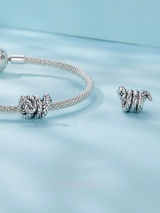 Macro shot of S925 sterling silver coiled snake bead with green gemstone eyes detail