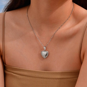 Close-up of heart-shaped locket necklace with sparkling rhinestones worn by a model