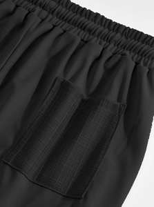 Detail view of the elastic drawstring waistband and woven texture on black linen pants