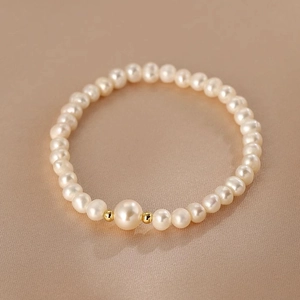 Elegantes Süßwasserperlenarmband mit großer Mittelperle auf champagnerfarbener Seide