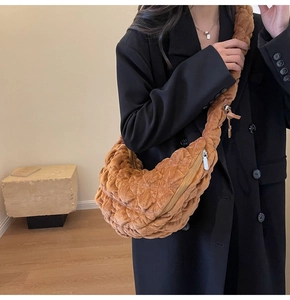 Detailed view of brown quilted velvet cloud bag worn by model in minimalist indoor setting