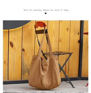 Brown canvas tote bag resting on a chair showing minimalist texture and quote detail