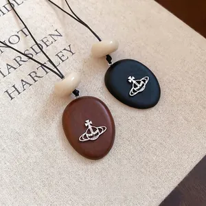 Vintage acrylic geometric Saturn pendant necklace with wooden texture on fabric background