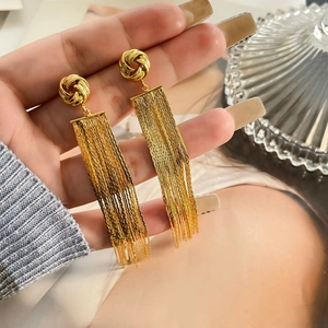 Detail of 18K gold plated long tassel chain earrings held by hand for scale display