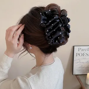 Elegant black polka dot silk satin hair clip shown on a brunette bun for a stylish look
