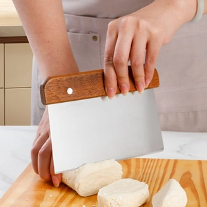 Dough scraper with wooden handle cutting dough on a board in a professional kitchen