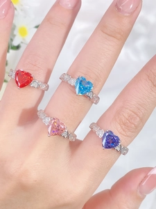 Close-up of four colorful heart-cut gemstones set in silver bands with sparkling accents