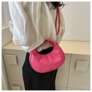 Detailed view of a pink crescent shoulder bag featuring smooth texture and zipper closure