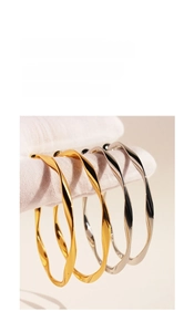 Detail showing twisted metallic texture on gold and silver wavy hoop earrings for women