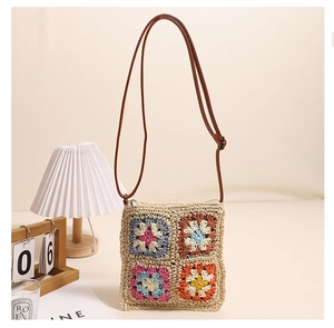 Close-up of handmade hollow flower crochet crossbody straw bag with vintage floral patterns