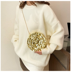 Fashionable gold rose acrylic evening bag with a metallic chain on a knit sweater