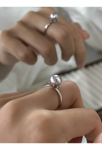 Dettaglio macro dell'anello con perla grigia lucida e montatura in argento a griffe