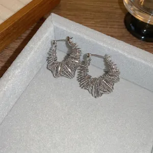 Irregular geometric silver hoop earrings with a textured bird nest wire design