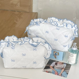 Detailed close-up of quilted cotton cosmetic bags with blue bow embroidery and ruffles
