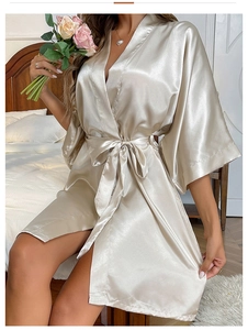 Close-up of champagne satin robe with silk texture, v-neck design, and belted waist detail