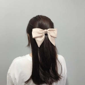 Detailed back view of a large cream satin bow hair clip styled in a half-up hairstyle
