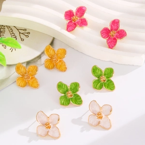 Close-up of colorful enamel flower stud earrings with golden petals and summer floral details