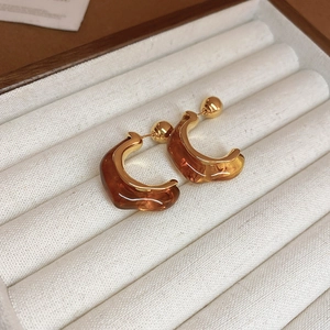 Close-up of amber resin C-hoop earrings with gold-plated metal in a velvet gift box
