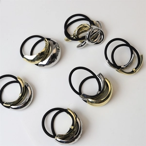 Close-up of polished gold and silver metallic charms on elastic hair bands with smooth finish