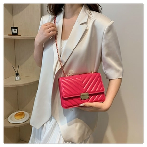 Detail of fuchsia quilted crossbody bag with V-shaped stitching and gold lock