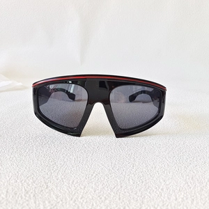 Close-up of black oversized shield sunglasses with a sporty red stripe and grey lenses
